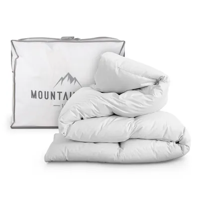 A white duvet is folded and placed next to its white storage bag, which has a mountain logo and text on it.