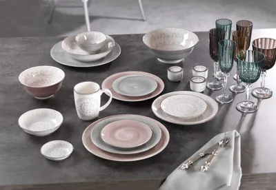 A collection of tableware, including plates, bowls, and glasses, arranged on a dark gray surface.