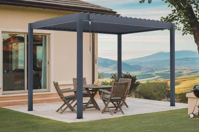 A patio area with a pergola, table, and chairs, overlooking a scenic landscape.