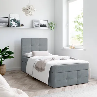 A bedroom with a single bed, shelf with pictures, and a window.