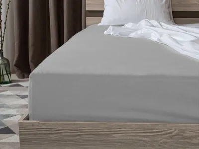 A close-up view of a grey fitted sheet on a bed.