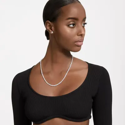 A woman wearing a black top and a silver necklace and earrings.