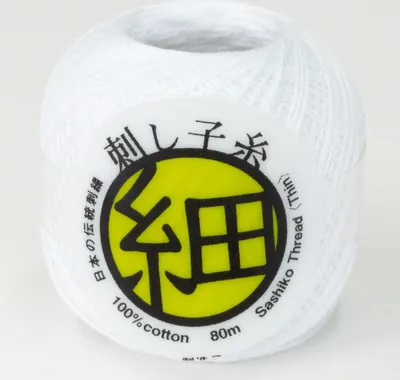 A spool of white Sashiko thread on a plain background.