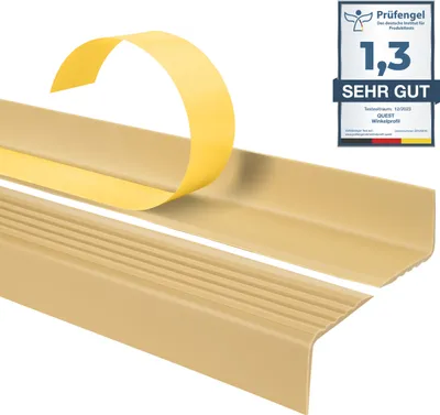 A close-up, angled view of a beige stair edge protector profile with its adhesive backing exposed, set against a white background. A German quality seal is visible in the upper right corner.