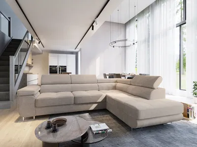 A modern living room with a large sectional sofa, coffee table, and stairs leading to an upper level. Large windows with sheer curtains allow natural light to fill the space.