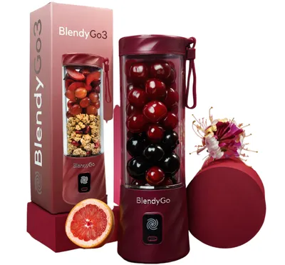 A product shot of a portable blender and its packaging, along with some fruit and a gift box.