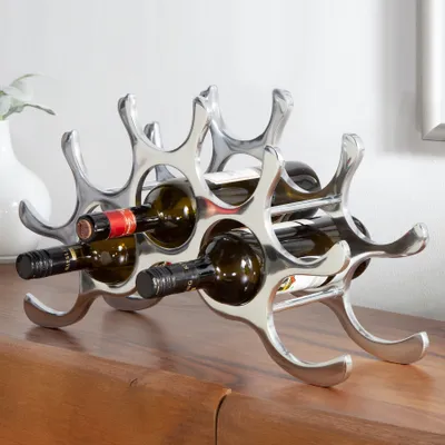 A modern, silver-colored wine rack holding several bottles of wine, placed on a wooden surface.
