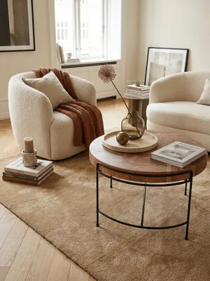 Eleganter runder Couchtisch aus massivem Akazienholz in einem hellen, luxuriösen Wohnzimmer, kombiniert mit einem beigen Sofa und einem weichen Wollteppich._#sku_SAFWL6.174#