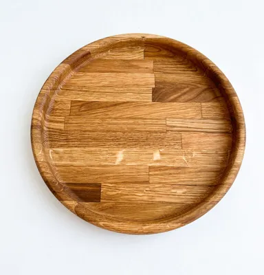 A top-down view of a round wooden serving platter on a white background.