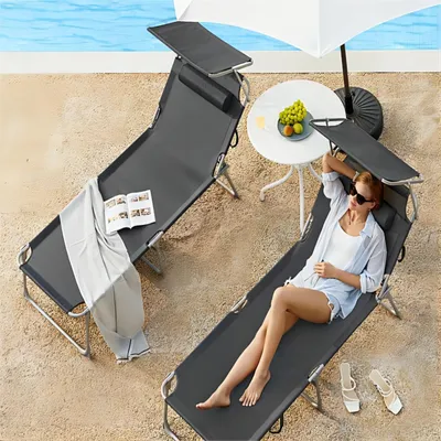 Two lounge chairs by a pool with a woman relaxing on one.