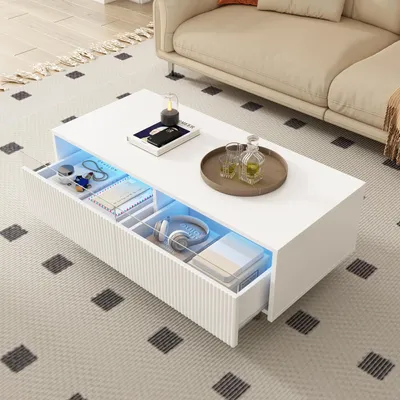 A modern white coffee table with LED lighting and storage drawers, placed in a living room setting with a sofa and rug.