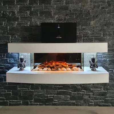 A modern electric fireplace with a white surround, set against a dark stone wall.