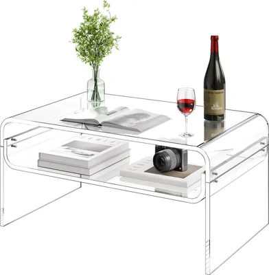 A transparent acrylic coffee table with books, a camera, a bottle of wine, and a glass of wine on it.