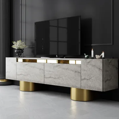 A modern TV stand with a marble-like finish and gold accents, placed in a dimly lit room with a large TV on top.