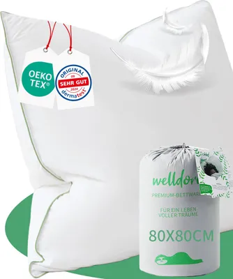 A white pillow with green trim is shown next to a packaged pillow and some feathers. There are also certification labels attached to the pillow.