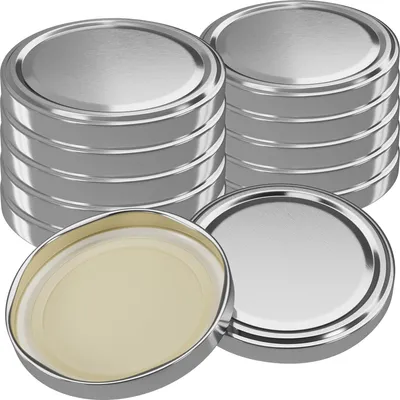 A stack of silver jar lids with one lid in the foreground showing the beige inner seal.