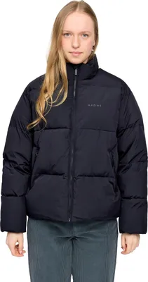 A woman wearing a black puffer jacket and grey pants, posing against a white background.