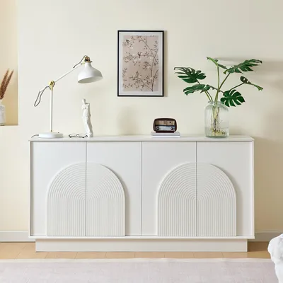 A white sideboard with arched doors is displayed in a room with a light-colored wall and floor.