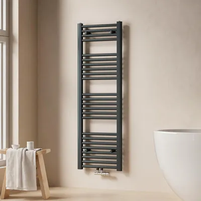 A dark grey towel radiator is mounted on a light beige wall next to a white bathtub. A wooden stool with a folded towel and some small containers is placed to the left of the radiator.