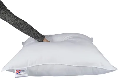 A hand is pressing down on a white pillow.