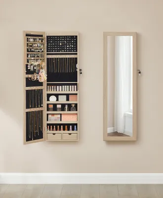 A jewelry cabinet with its door open, displaying various jewelry and makeup items, stands next to a full-length mirror on a wall.
