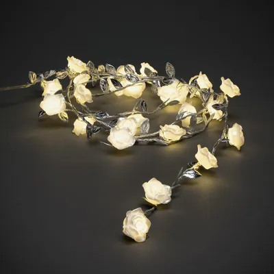 A string of LED lights shaped like roses with silver leaves on a dark gray background.