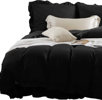 A close-up view of a black duvet cover with ruffled edges and several pillows on a bed.