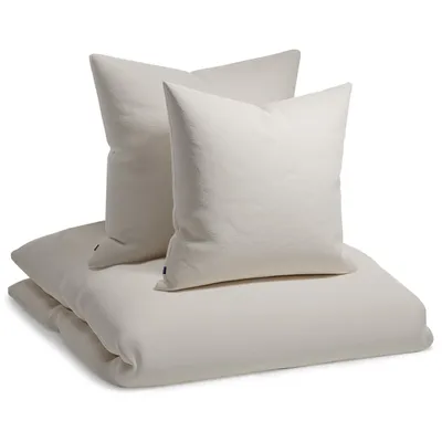 A stack of beige bedding items, including two pillows and a folded duvet cover, presented on a white background.
