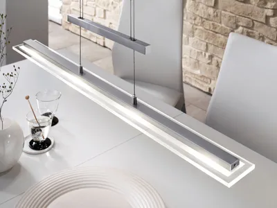 A modern linear pendant light hangs over a white dining table.