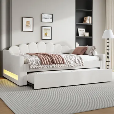 A white daybed with a pull-out trundle bed is shown in a bedroom setting.