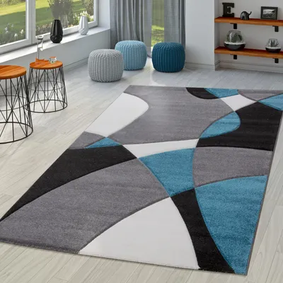 A modern living room with a geometric rug, side tables, and poufs.
