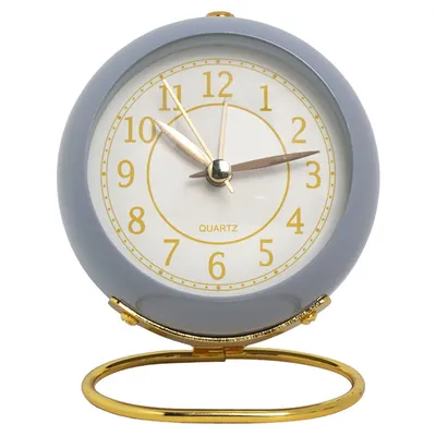 A close-up studio shot of a round, gray analog alarm clock with a gold stand.