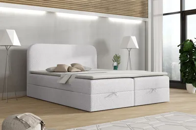 A modern bedroom with a white boxspring bed.