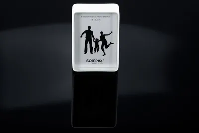 A white photo frame with a silhouette of a family is displayed on a reflective black surface.