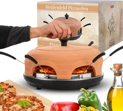 A hand is shown lifting the lid of a terracotta pizza oven, with pizzas inside and ingredients like bell peppers and olive oil nearby. A product box is visible in the background.