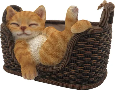 A decorative figurine of a sleeping orange cat in a woven basket.