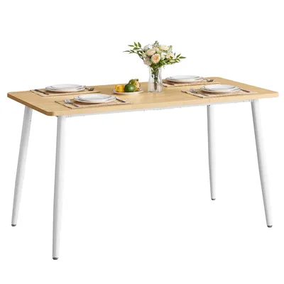 A dining table set with placemats, plates, and a vase of flowers.