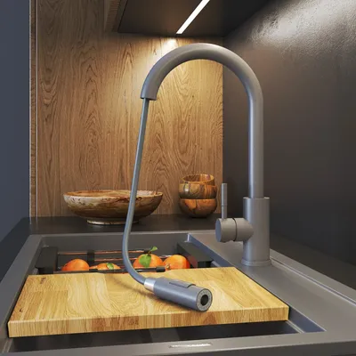 A modern kitchen sink area with a faucet, cutting board, and fruit.