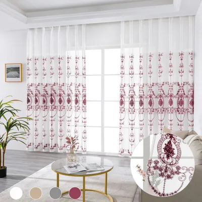 A living room scene with sheer curtains, a coffee table, and a plant.