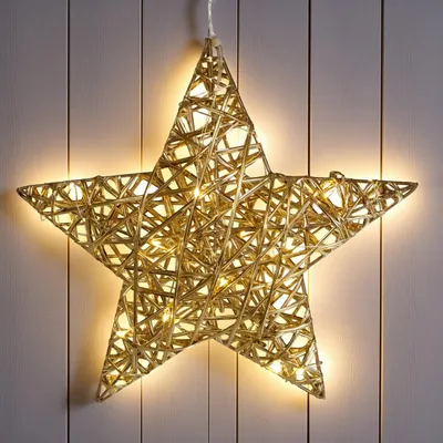 A decorative star-shaped light fixture hanging against a wooden wall.
