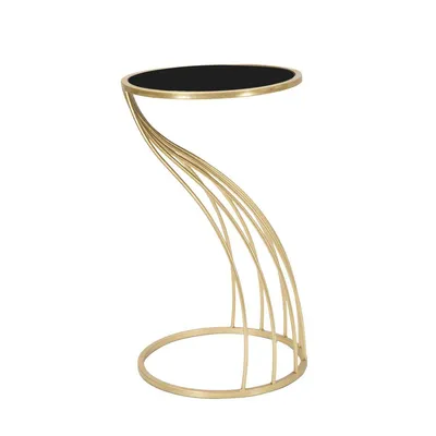 A modern side table with a black circular top and a gold, sculptural base.