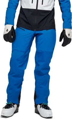 M Dawn Patrol Hybrid Pants von Black Diamond in Blau; getragen von einer Person mit weißen Skischuhen und Handschuhen.