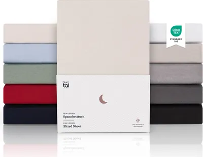 A stack of fitted sheets in various colors, with a product box in the foreground.