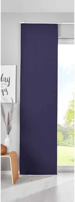 A dark blue sliding curtain panel hangs in front of a window with a view of trees and sky. A small wooden stool with a decorative object and a vase with dried grass are visible to the left.