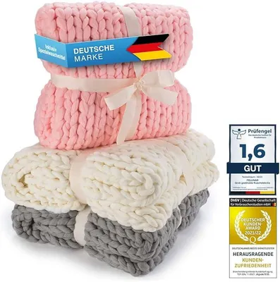 Three folded blankets stacked on top of each other, with marketing labels and awards.