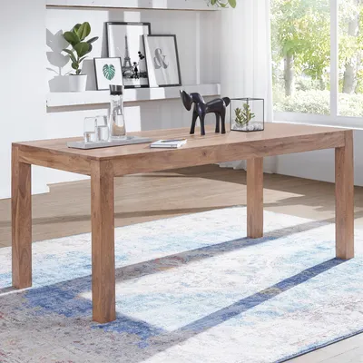 A wooden dining table is set in a room with a rug and decorative items on a shelf.