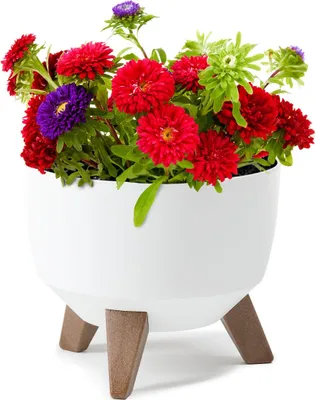 A white planter with wooden legs holding a bouquet of colorful flowers.