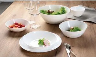A collection of white ceramic bowls and plates filled with food, set on a wooden table.
