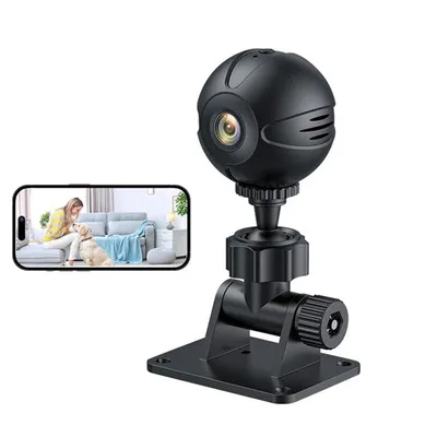 A black mini-WLAN surveillance camera with a stand is shown next to a smartphone displaying a live feed of a woman and a dog in a living room.