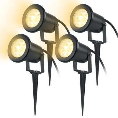Four black garden spotlights with stakes, emitting warm yellow light.